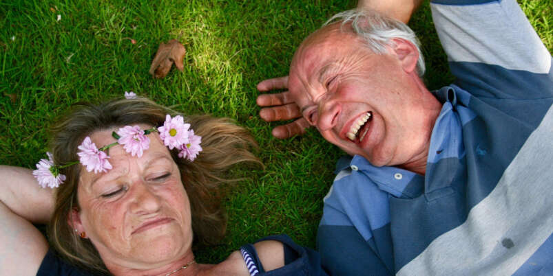 Seniorenpaar liegt entspannt im Grass